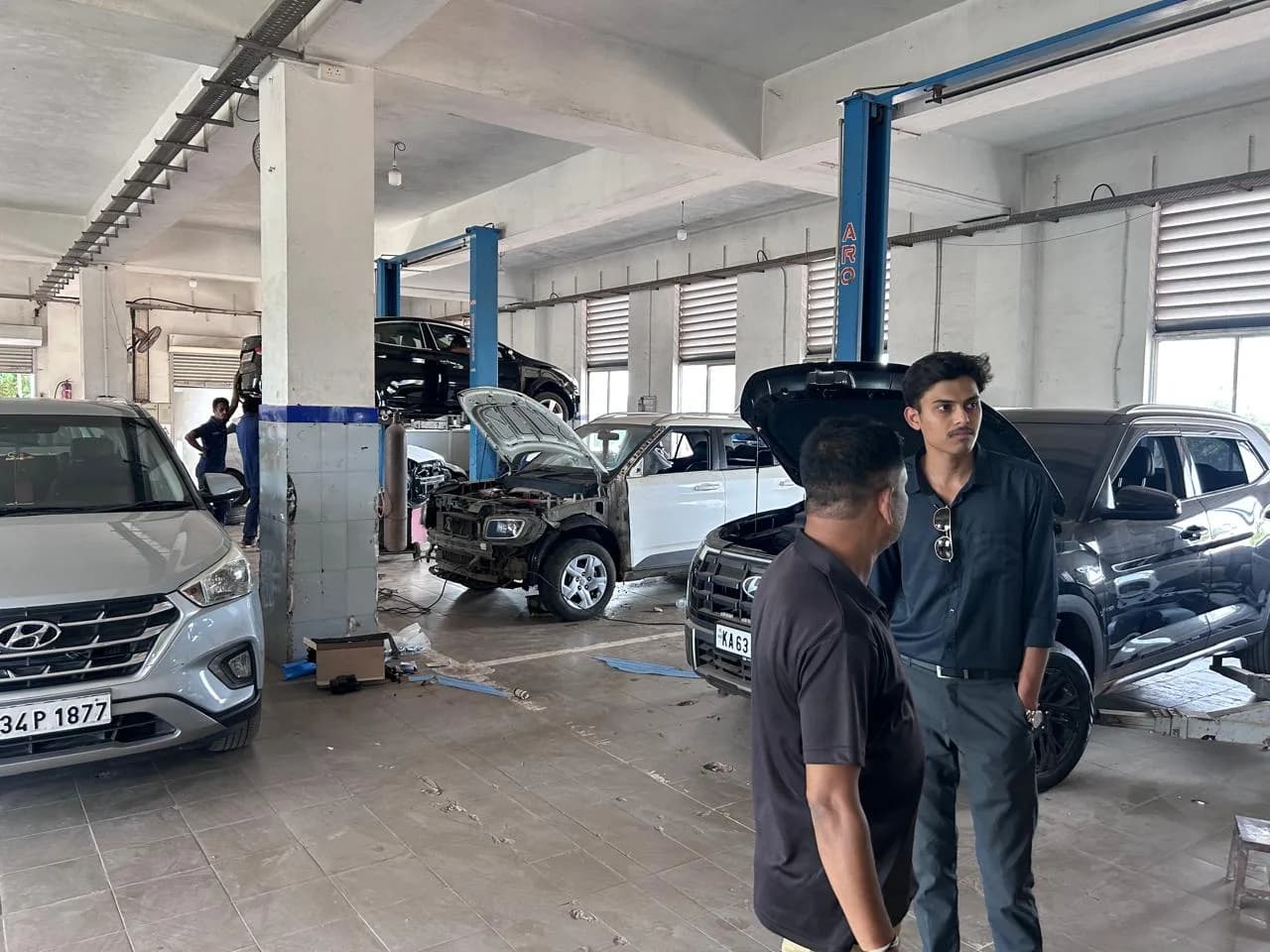 Cars raised on service-bay lifts at an automotive workshop, with the team observing on the floor