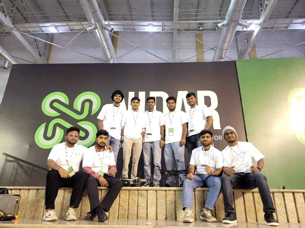 Team in matching shirts photographed at a technology expo beside a drone
