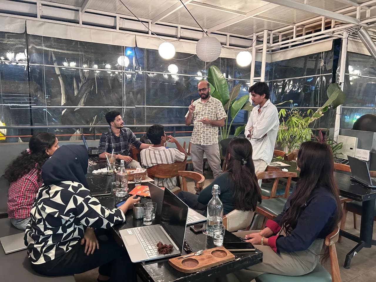 A mentor talking through work with interns seated around a table with laptops