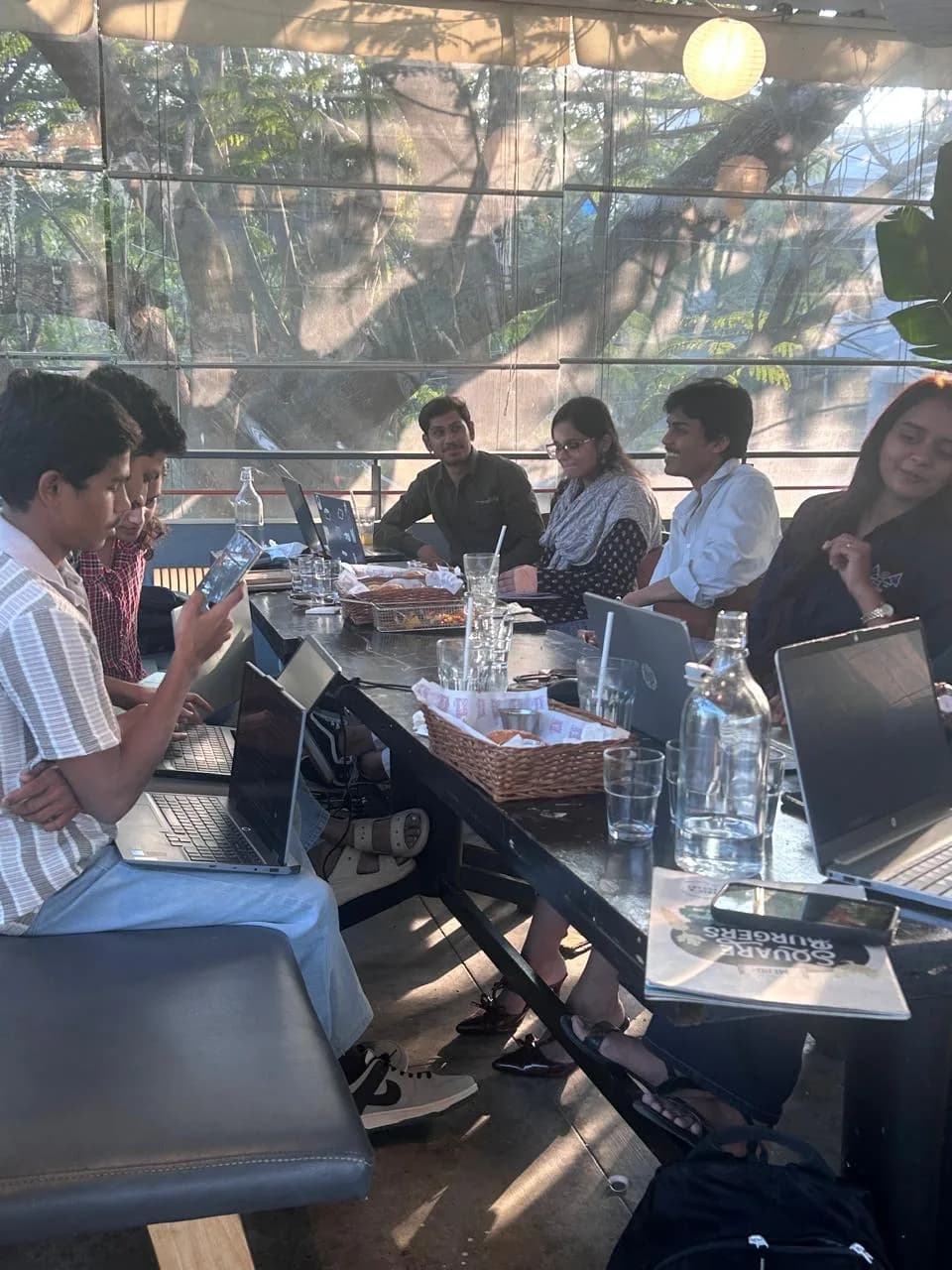 Interns working on laptops around a table in a co-working space