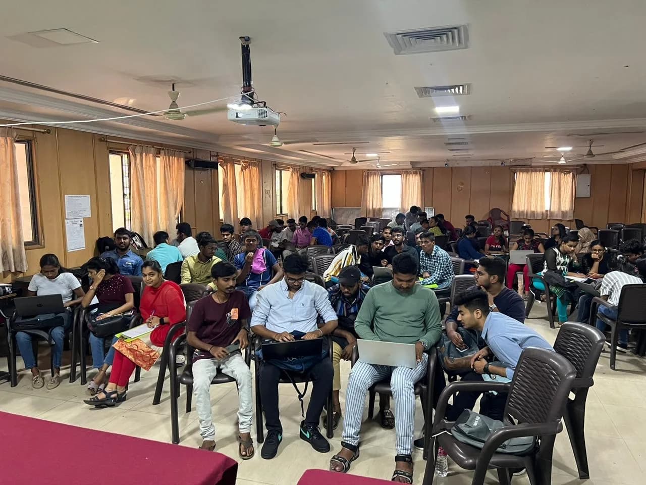 Students with laptops seated across a college hall during a workshop