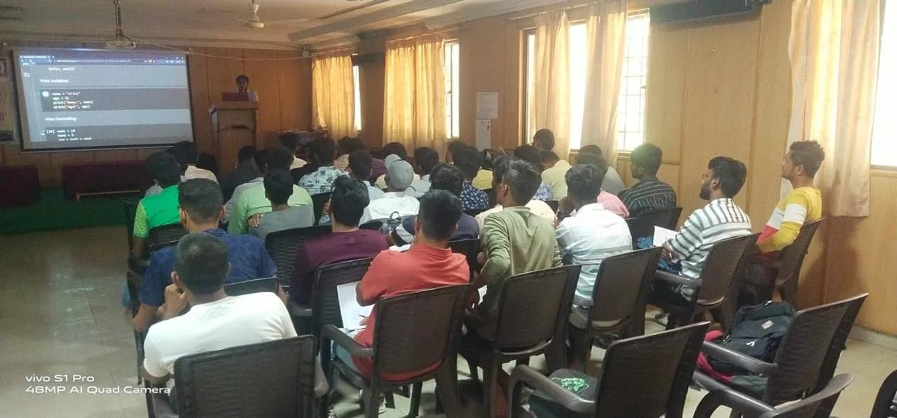 A full hall watching a Python basics session projected on screen