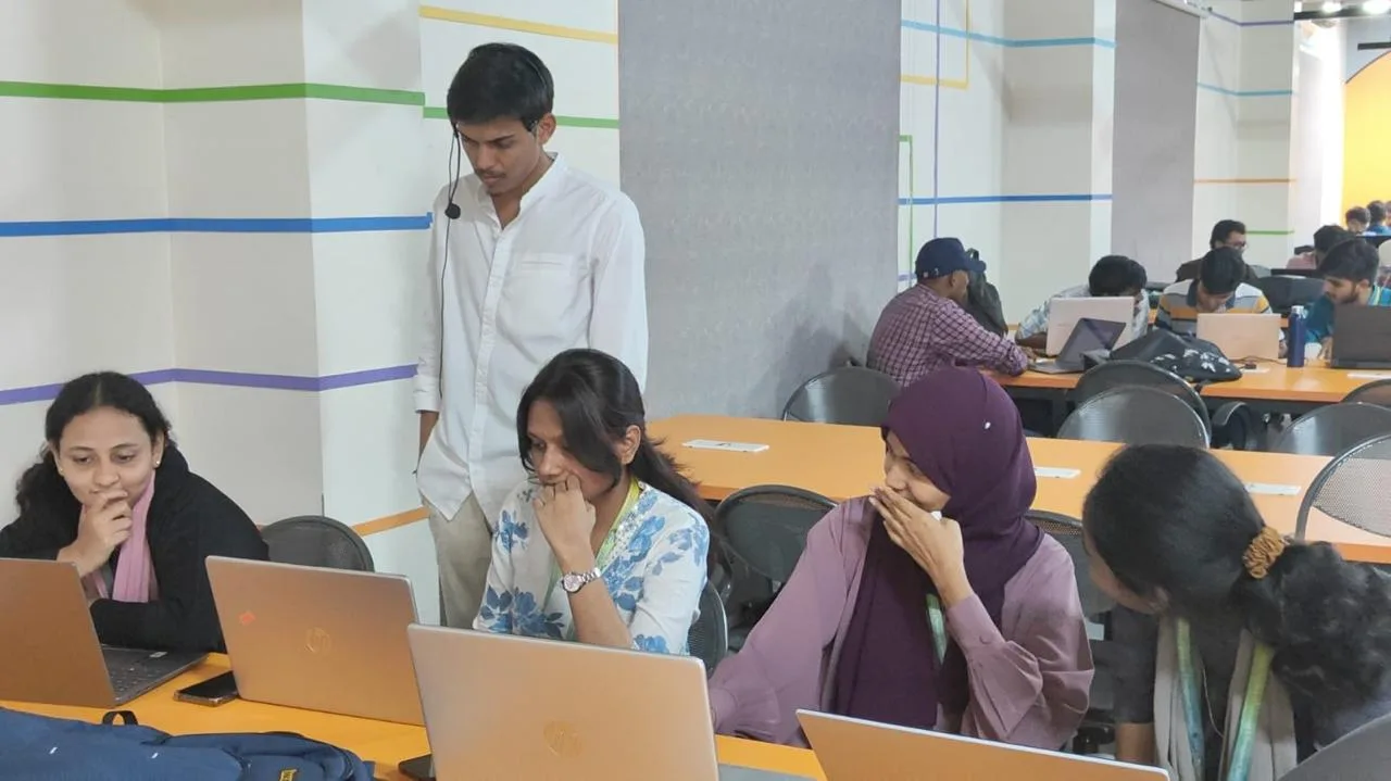 Instructor walking between rows of students working at laptops
