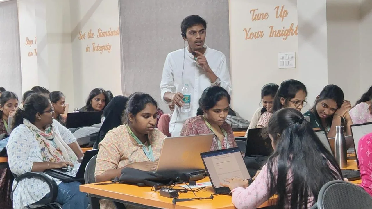 Instructor standing among students working at laptops in a computer lab